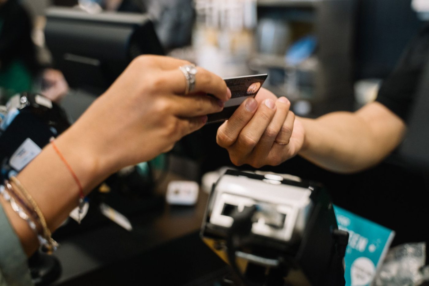 Hand som betalar med ett bankkort i en kortläsare i en butik